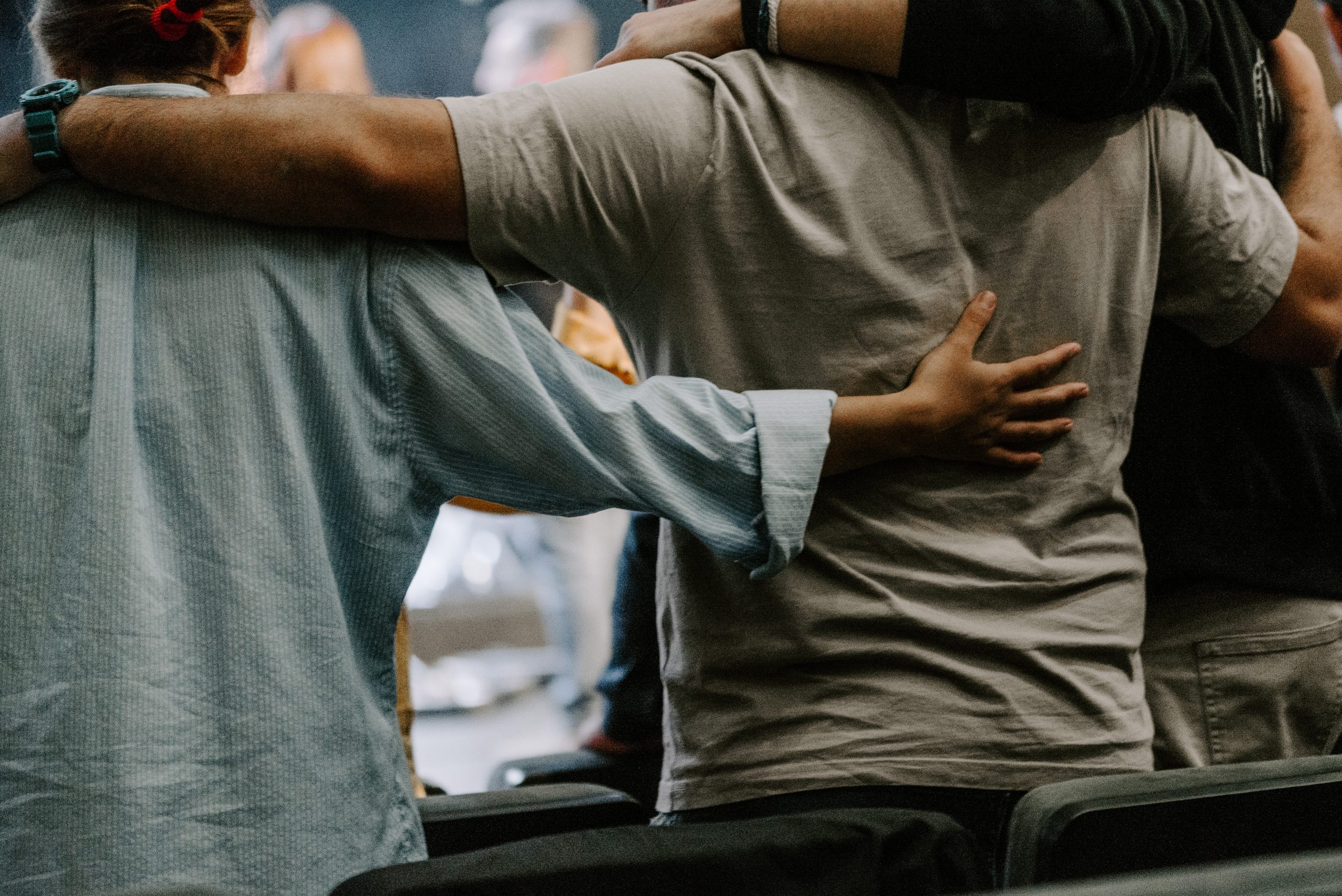 a group of people in circle praying and embracing each other